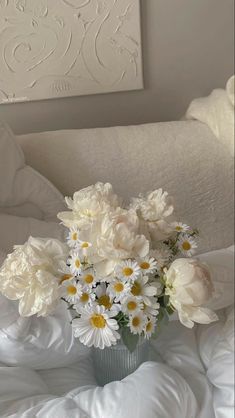 a vase filled with white flowers on top of a bed