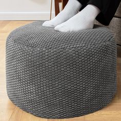 a person sitting on top of a gray ottoman