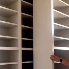 a man standing next to a tall white book shelf filled with lots of open shelves