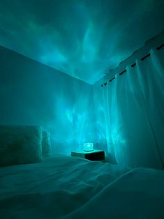 a bed with white sheets and blue lights on the walls in a room that is dimly lit