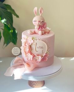 a pink cake decorated with flowers and a bunny on top