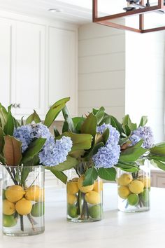 three vases filled with lemons and blue flowers