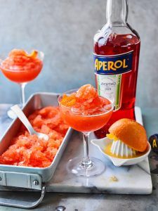 two glasses filled with orange jello next to a bottle of aperol