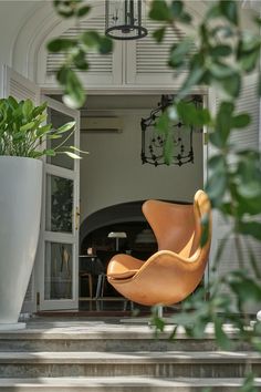 an egg chair is sitting on the steps in front of a door and potted plant