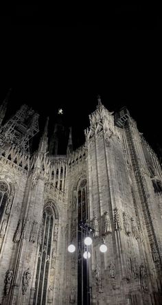 the cathedral is lit up at night with two street lamps in front of it and one light on