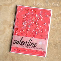 a valentine's card with pink and red sequins on it, sitting on a marble surface