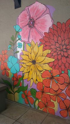 an artistic mural painted on the side of a building with flowers and leaves in bright colors