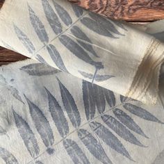 two pieces of fabric with leaves on them sitting next to each other and one piece of wood in the background