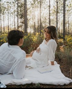 two women sitting on a blanket in the woods