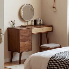 a bedroom with a desk, mirror and chair in it's corner next to a window