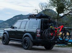 a black suv parked next to a lake with a bike on the back of it