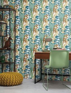 a green chair sitting in front of a wooden desk next to a wallpapered wall