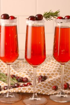 three wine glasses filled with cranberry juice and garnished with fresh cherries