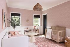 a baby's room with pink and white decor, including a crib, chair, table, and rug