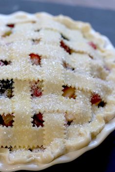 a freshly baked pie sitting on top of a blue tablecloth covered plate with powdered sugar