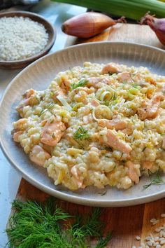 a white plate topped with macaroni and cheese covered in salmon on top of a wooden cutting board