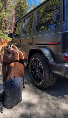 a large brown bag sitting on the ground next to a black car and suitcases