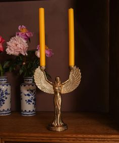 two candles are sitting on a table next to vases with flowers