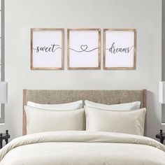 two framed pictures hang above a bed in a room with white linens and pillows