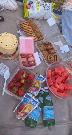 a table topped with lots of food next to bottles of juice and cookies on top of it