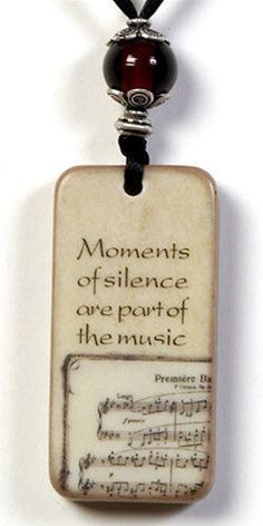 a necklace with a quote on it that says, moments of silence are part of the music