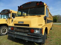 two yellow school buses parked in a field