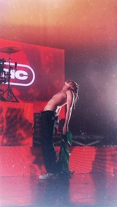 a naked woman standing on top of a stage next to a drum set in front of a red screen