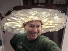 a woman wearing a large hat with lights on it's head and smiling at the camera