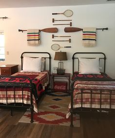 two beds in a room with wooden flooring and wall mounted paddles on the wall