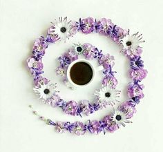 a cup of coffee surrounded by purple and white flowers