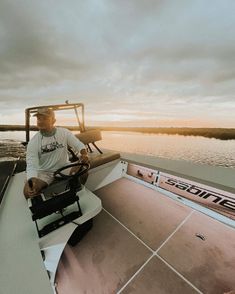 a man sitting on the back of a boat at sunset with his steering wheel up