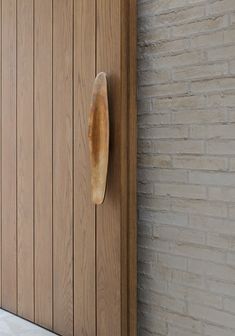 a door with a wooden handle on it next to a brick wall and wood paneling