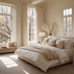 a large white bed sitting in a bedroom next to two windows