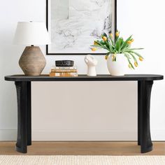 a black table with two vases on it and a lamp in front of it