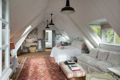 an attic bedroom with two beds and couches