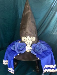 a blue and black hat with flowers on it sitting on top of a wooden table