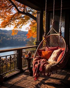 a hammock hanging from a porch next to a tree with fall foliage in the background