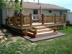 a deck with steps and planters on the grass