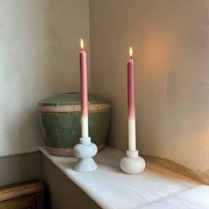 two candles sitting on top of a white mantle