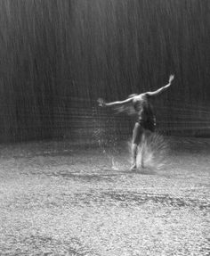 a man standing in the rain with his arms outstretched