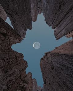 the moon is seen through some tall rocks