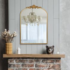 a fireplace with a mirror above it and a teddy bear sitting on the mantel