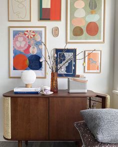 a living room with art on the wall and pictures hanging above it's sideboard