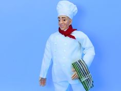 a man in a chef's outfit is holding a green bag and smiling at the camera