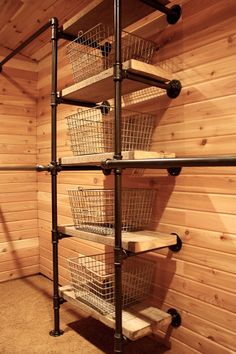 the shelves are made out of metal pipes and wood planks, with baskets on them