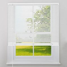 an open window with white blinds and green grass in the foreground, against a white wall