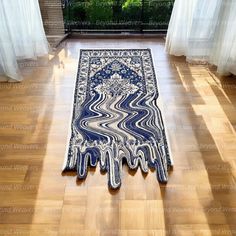 a blue and white area rug on the floor in front of windows with sheer curtains