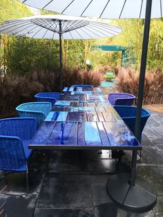 an outdoor table with blue chairs and umbrellas