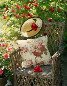 a chair with a hat on top of it in front of some flowers and plants