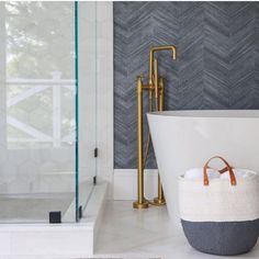 a bathroom with a tub, shower head and towel basket on the floor next to it